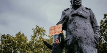 Protestor by statue of Churchill