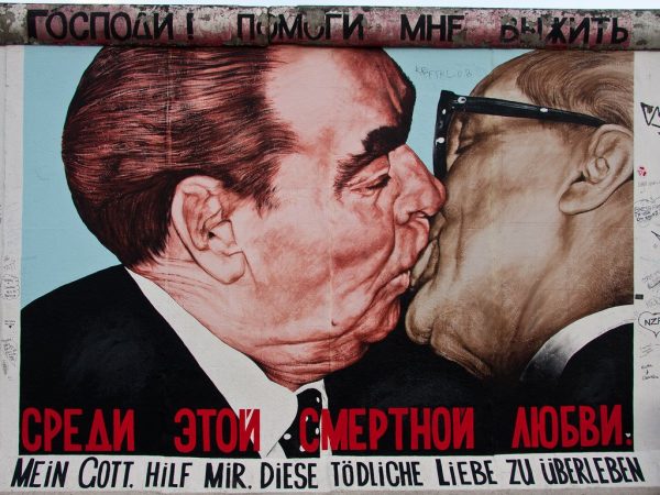 Two middle aged men kiss passionately in a graffiti on the Berlin Wall, representing satirically the close links between the East German and Russian leaders