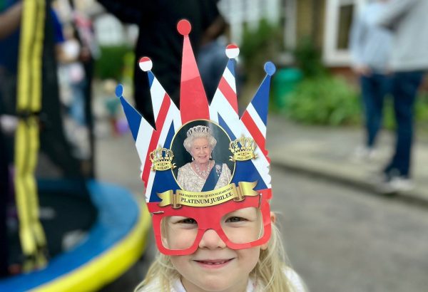 Image of little girl with a cardboard crown with HM the Queen on.