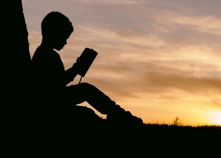image of a child in silhouette reading a book
