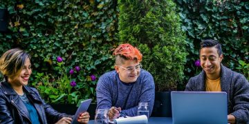 Three smiling young people enjoying working outside.