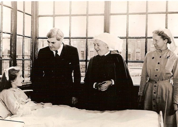 Anenurin Bevan standing beside a hospital bed on the first day of the NHS.