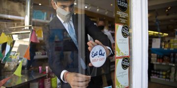 Rishi Sunak sticks an Eat Out to Help Out sticker on a window