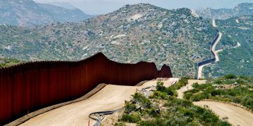 Mexican-American border: brown fencing with mountains in the background