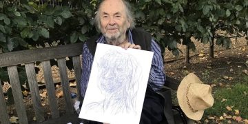 Quentin Blake sitting on a bench with some of his imaginary portraits.