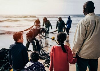 A group of people wait on the seashore
