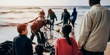 A group of people wait on the seashore