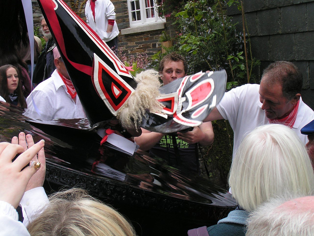 Adjustments being made to the mask of the red 'Oss in Padstow, Cornwall. Photo credit: Nomis Elaws on Wikimedia Commons.
