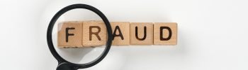 magnifying glass in front of the word fraud