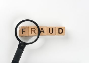 magnifying glass in front of the word fraud