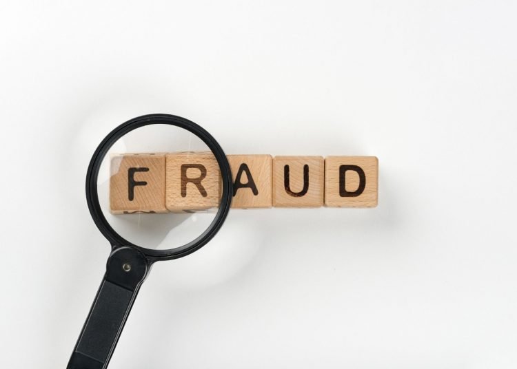 magnifying glass in front of the word fraud