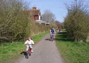 Child and adult cycling on the Cuckoo Trail path