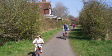 Child and adult cycling on the Cuckoo Trail path
