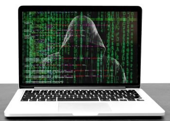 Photo of a hooded character sitting at a computer