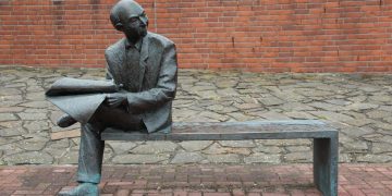 Sculpture of man reading newspaper.