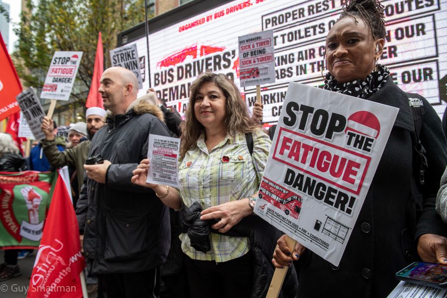 Three bus drivers hold signs about the safety of their terms and conditions.