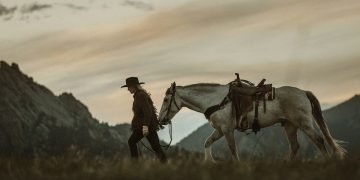 woman in cowboy hat leading a horse