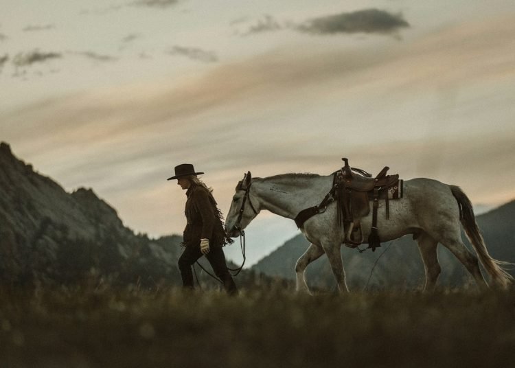woman in cowboy hat leading a horse