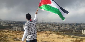Palestinian waving a flag in wasteland
