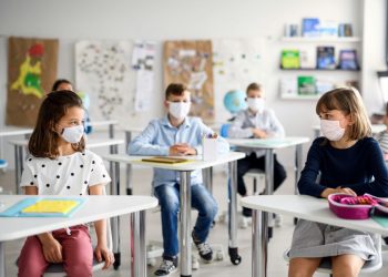 children with masks on in a classroom