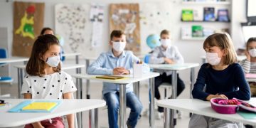 children with masks on in a classroom
