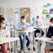children with masks on in a classroom
