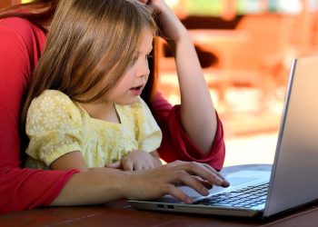A child in a parent's arms looking at a computer