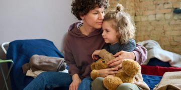 Adult hugging a child holding a teddy