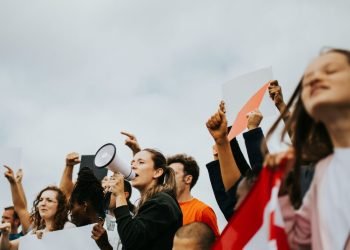 Lady with a microphone surrounded by protestors
