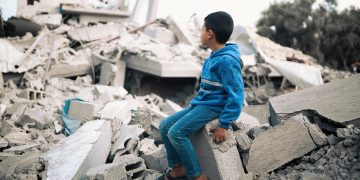 Boy sitting on destroyed building in Gaza.