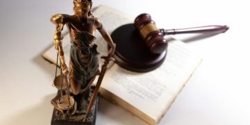 Statue of justice, gavel, and open book on table