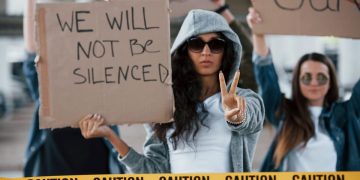 Woman with a cardboard sign making a peace sign