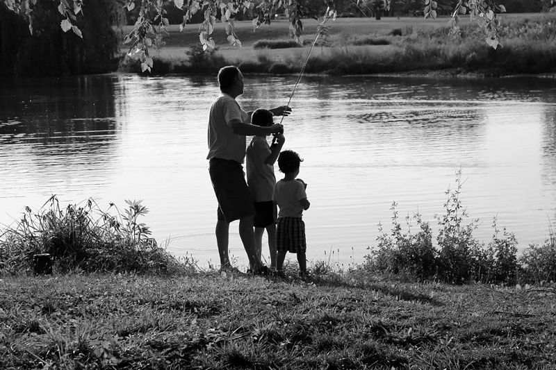 Dad and two boys fishing on a lake.
