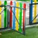 Colorful playground fence gate with blue, yellow, green, and red slats and a gray metal frame.
