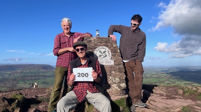 three men at a trig point on Brecon Beacons